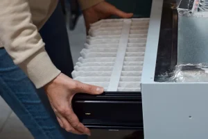 DIY Heating Mistakes, Grand Peninsula - Man replacing furnace filter at home