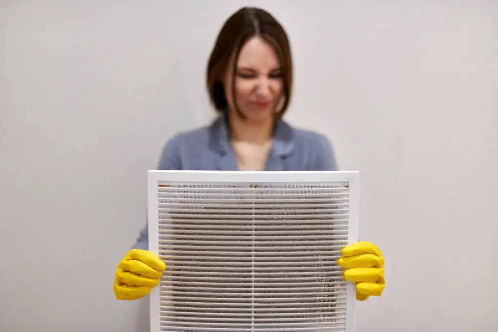Duct cleaning frequency - Woman holding a dirty duct vent