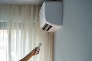 Person pointing a remote control at a ductless mini-split ac unit.