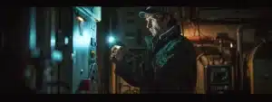 a mechanic holding a flashlight inspecting the electrical panel of a residential heater in a dimly lit basement.